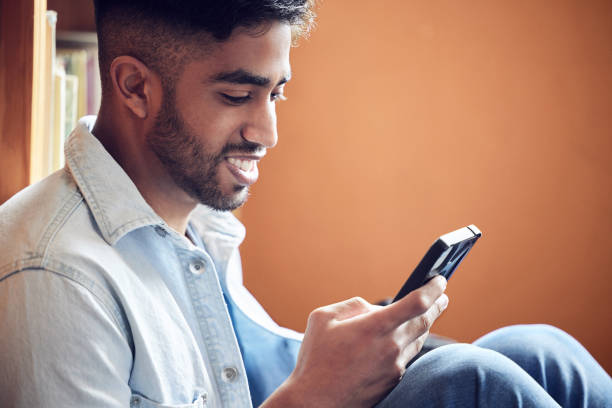 istock Shot of a young man using a smartphone in a library at university 1362700814