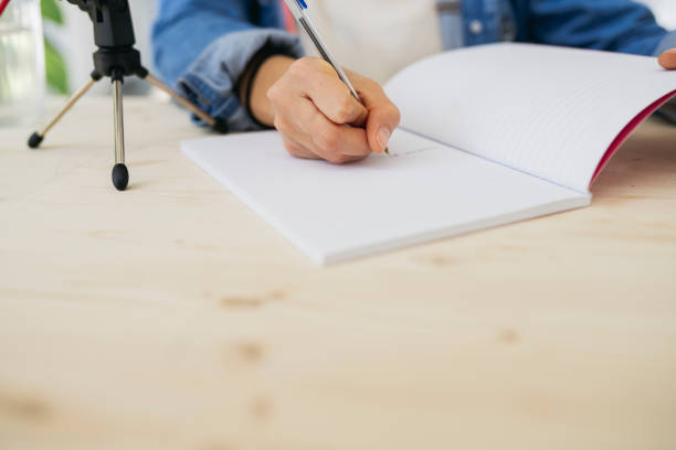 istock woman writing in notebook with microphone podcast 1362702773