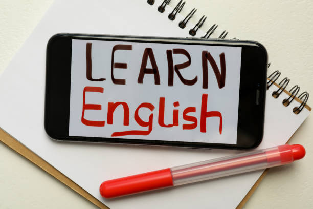 istock Smartphone with phrase Learn English, notepad and pen on white background, flat lay 1362704424