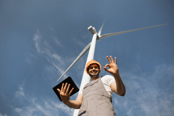 istock Man using tablet and and showing thumb up near wind turbines 1362712571