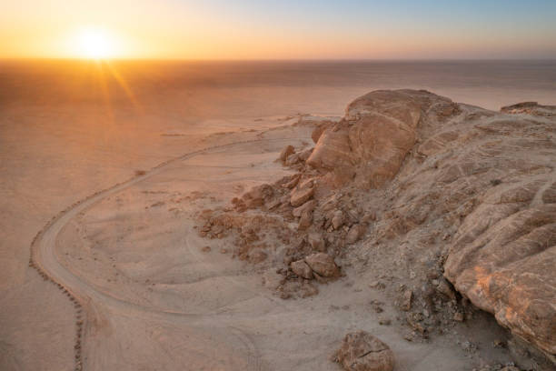 Sunset in desert with camel caravan silhouette on sand dunes