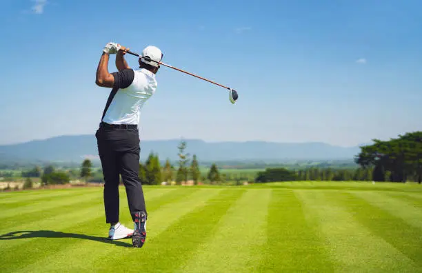 Photo of Asian man golfing on the course. In summer