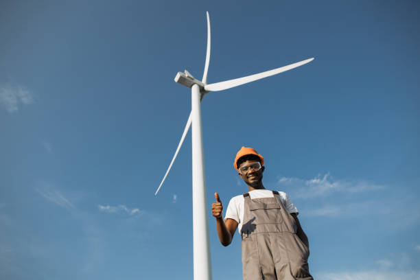 istock Engineer in uniform gesturing with fingers thumbs up at windmill farm 1362712732