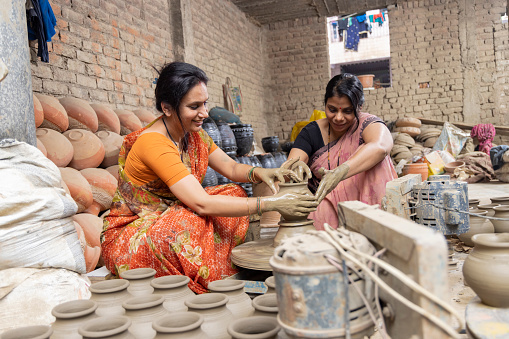 istock Two women working on potters wheel making a clay pot. 1362713622