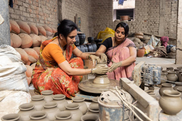 istock Two women working on potters wheel making a clay pot. 1362713638