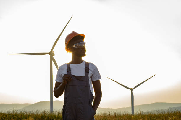 istock Technician in uniform posing on farm with wind turbines 1362713871