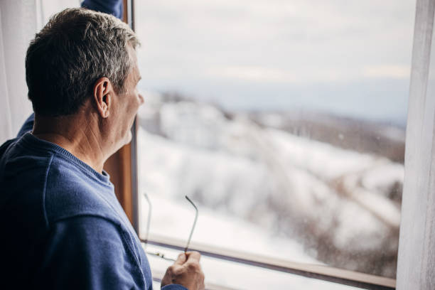 istock An older man is standing by the window 1362715541