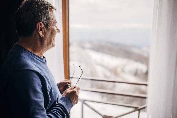 istock An older man is standing by the window 1362715577
