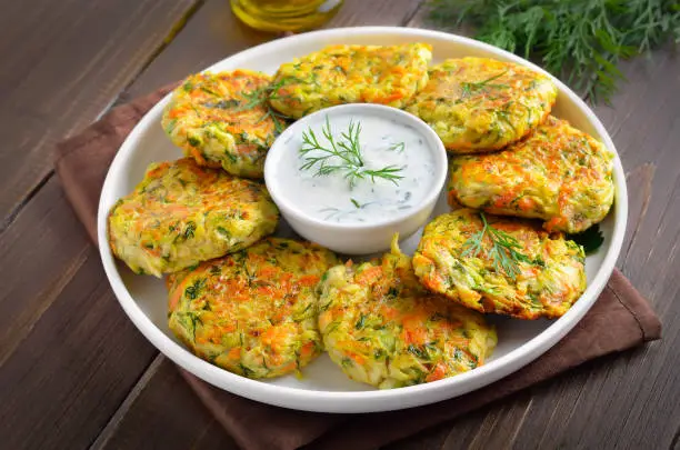 Vegetable cutlets from zucchini, carrot, herbs in white plate