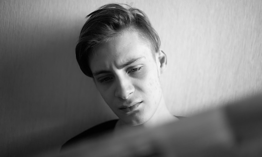 Young man reading a newspaper with emotions on his face isolated