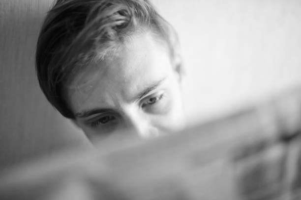 istock Young man reading a newspaper with emotions on his face 1362718803