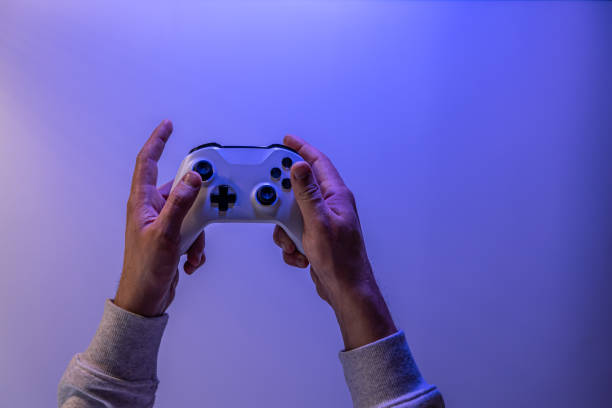 istock Male hands hold a gamepad on a blue background, copy space. 1362718939