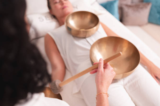 Sound healing therapist practicing Singing bowls in sound healing therapy with two women mantra stock pictures, royalty-free photos & images