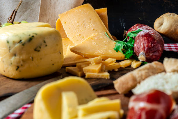 A delicious piece of spiced cheese and provolone on a cutting board on a rustic table. Concept of natural, organic and healthy food. A normal view delicious piece of spiced cheese and provolone on a cutting board on a rustic table. Concept of natural, organic and healthy food. salumeria stock pictures, royalty-free photos & images