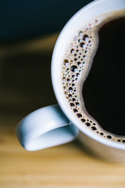 A closeup shot of a cup of black coffee with tiny bubbles stock photo