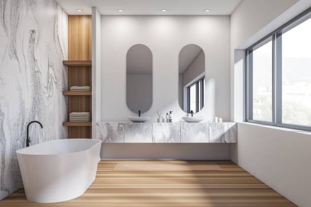 istock Bright bathroom interior with two sinks, bathtub, oval mirrors, window 1362723693