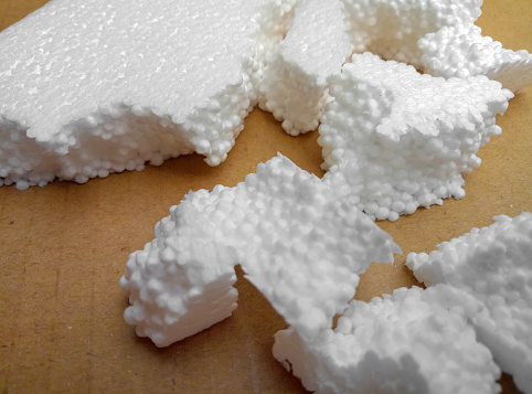 a bunch of crushed white styrofoam foam on a brown cardboard. Fractional foam. waste bearing materials for packaging and other industries