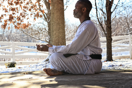 Martial artist meditating outdoors snow in the background.