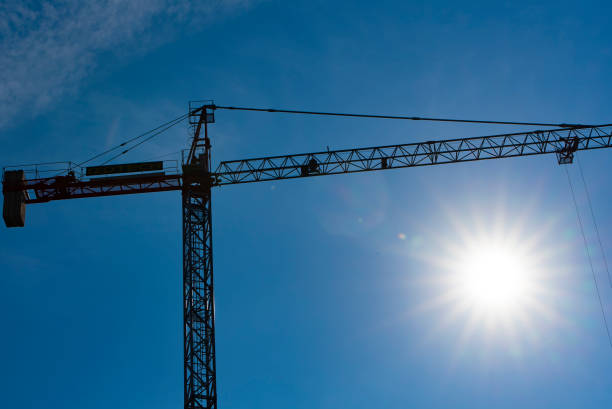 istock Construction crane on construction site agains the blue sky and the sun, back lit 1362728613