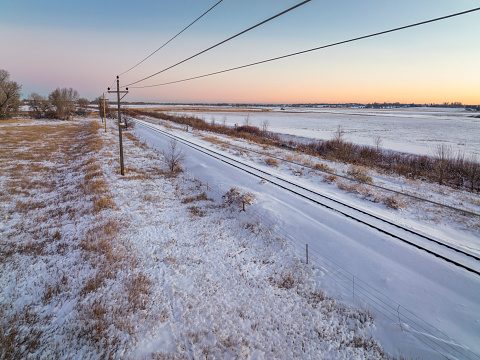 winter dusk over Colorado plains with railroad tracks, power line and irrigation ditch, aerial view