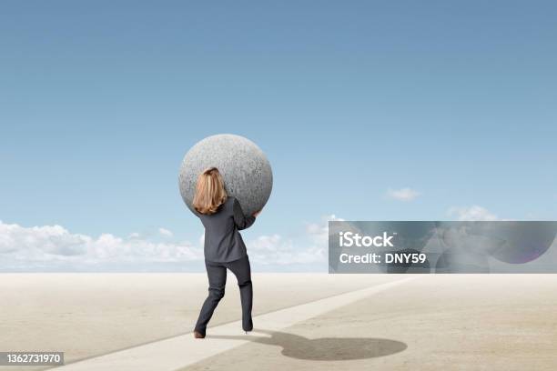 Woman Struggling To Carry Large Round Sphere Toward The Horizon Stock Photo - Download Image Now