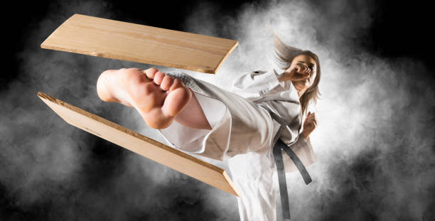 Woman in kimono practicing. Breaking board Woman in kimono practicing. Fighter concept. Breaking board. Smoke background martial arts stock pictures, royalty-free photos & images