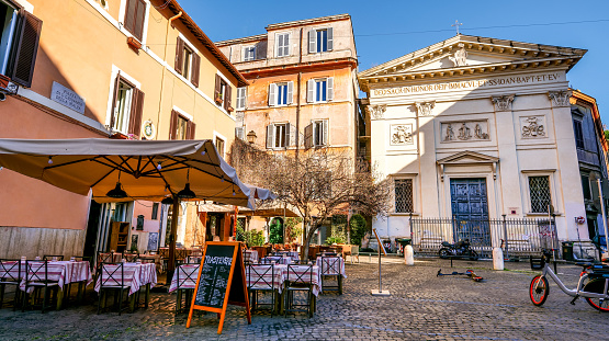 A quiet and picturesque little square in the ancient Trastevere district, in the historic heart of Rome. On the right the church of San Giovanni della Malva, built in 1851 on the site of an ancient medieval church of 1123 which was later demolished. This church is the seat of the Albanian Catholic community residing in Rome. Trastevere is an iconic district of the Eternal City, due to the presence of countless artistic and historical treasures, monuments and ancient Romanesque and Baroque churches, but also for its squares and alleys to be explored freely, where it is easy to find typical restaurants, pubs, small shops of artisans and scenes of daily life with the original Roman soul. In 1980 the historic center of Rome was declared a World Heritage Site by Unesco. Super wide angle and 16:9 image in high definition format.