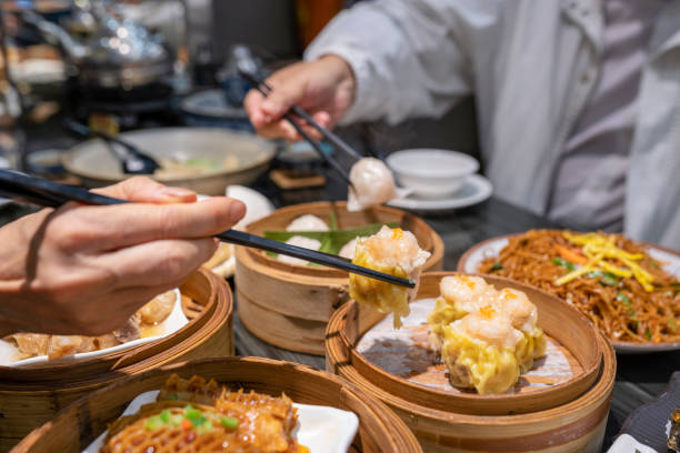 People eating Guangdong dum sum with chopsticks in the restaurant Dum sum including Shrimp Dumpling, Shumai, Honeycomb Tripes, Fried Noodles, Steamed Ribs, Fried Turnip Cake, Peach Gum Egg Tart, Cheesecake in the restaurant in Guangzhou, Guangdong. chinese ethnicity china restaurant eating stock pictures, royalty-free photos & images