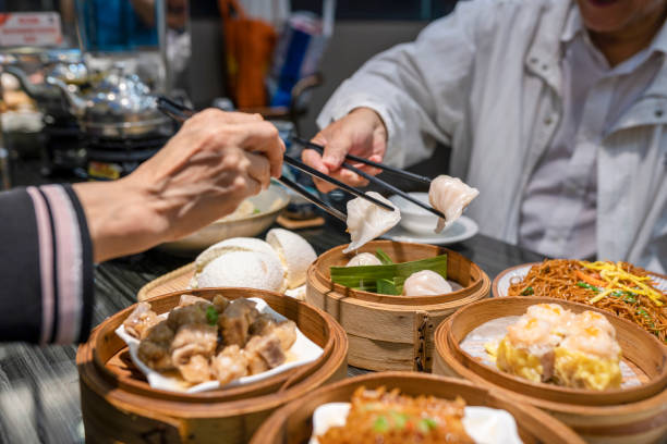 personnes mangeant la somme de dum de guangdong avec des baguettes dans le restaurant - eating men food chopsticks photos et images de collection