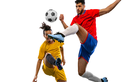 Close-up. Soccer or football players in motion on grass flooring isolated on white background. Sportsmen wearing football kit jumping and running. Concept of motion and action, sport, lifestyle.
