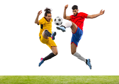 Going forward. Soccer or football players in motion on grass flooring isolated on white background. Sportsmen wearing football kit jumping with ball. Concept of action, sport, sports games.