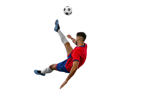 Powerful, flying and jumping above the field. Young football soccer player in action, motion isolated on white background. Concept of sport, movement, energy and dynamic, healthy lifestyle.