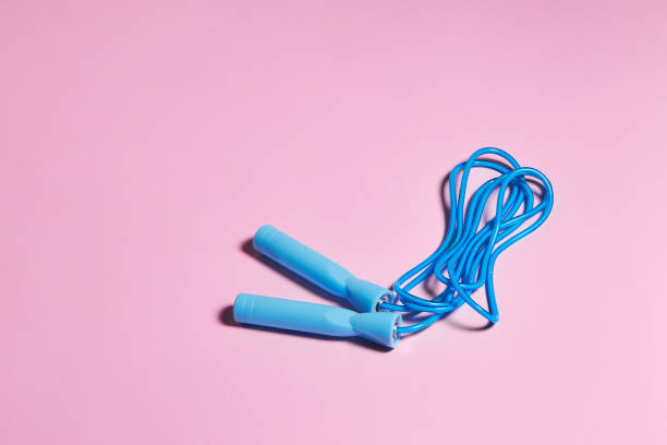 Blue jump rope or skipping rope  on a pink background. Sports, fitness workout concept.