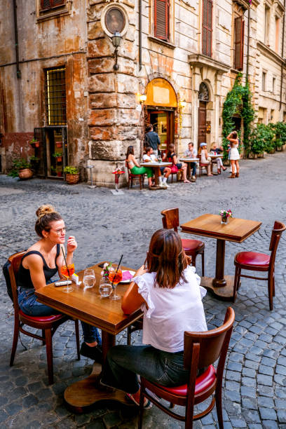 некоторые туристы наслаждаются жизнью, сидя в открытом кафе в историческом и барочном центре рима. - piazza navona стоковые фото и изображения