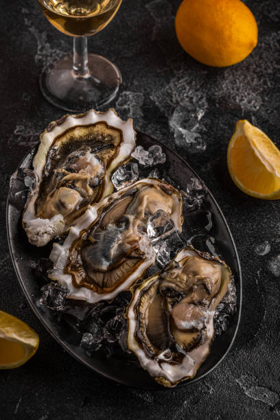istock Fresh oysters close-up on ice served with lemon and wine. 1362740941