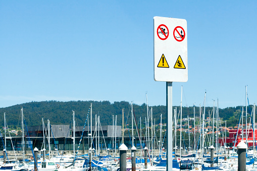 Warning signs and symbols seen on harbor dock. Marina in  Rías Baixas, Pontevedra province, Galicia, Spain. Copy space available on the left.