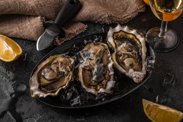 istock Fresh oysters close-up on ice served with lemon and wine. 1362741101