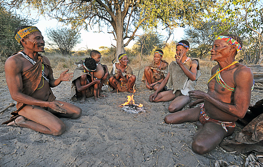 San bush people play a traditional game whilst seated around their fire, Makgadikgadi Pans, Botswana, Southern Africa. The San are an ancient indigenous tribal people who inhabited much of southern Africa and although few in number today remain proud of their culture, ancestry and traditional ways of dress, customs and behaviour that included subsistence hunting and foraging