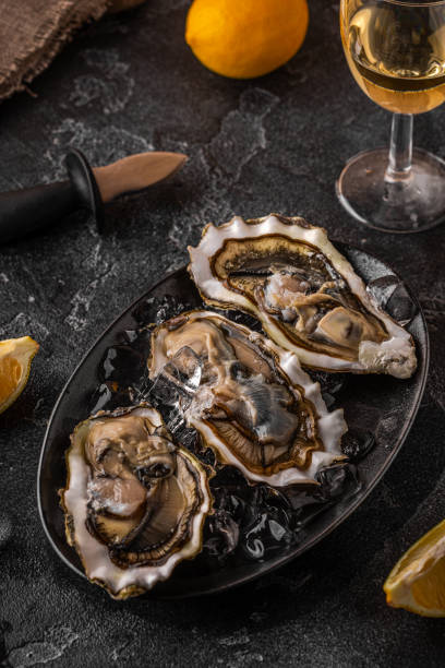 istock Fresh oysters close-up on ice served with lemon and wine. 1362744374