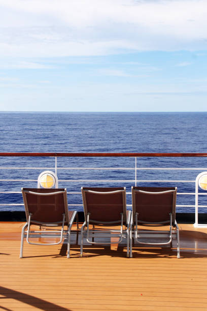 Three lounge chairs on a ship deck facing the ocean. stock photo