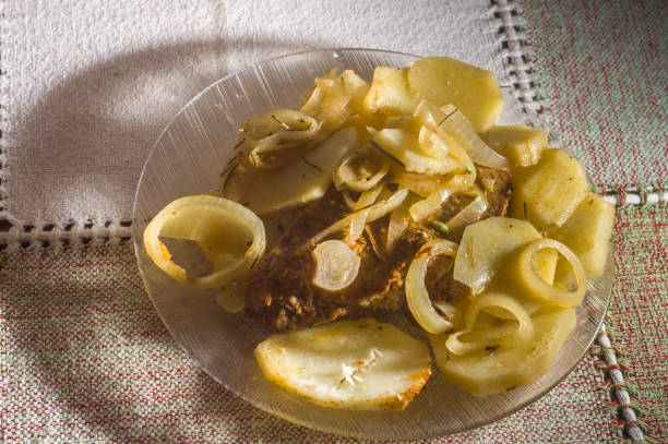 pork and potatoes on a simple plate on a family-friendly table, copy space on the left