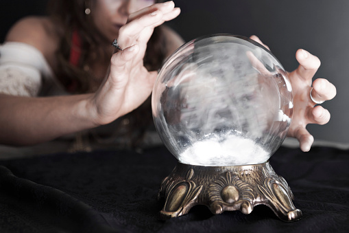 A fortune teller looking into a glowing crystal ball.