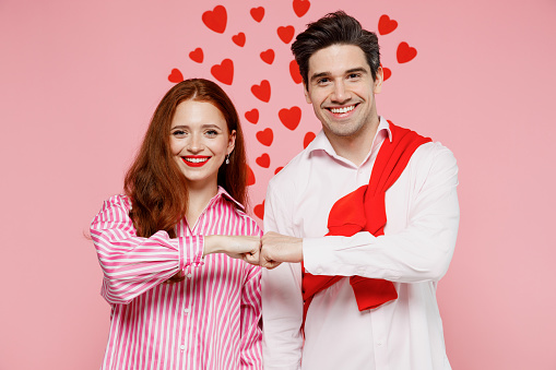 Young smiling couple two friends woman man 20s in casual shirt look camera do fistbump gesture isolated on plain pastel pink background studio portrait. Valentine's Day birthday holiday party concept