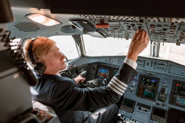 istock Male pilot turning switch on overhead panel in cockpit 1362766137