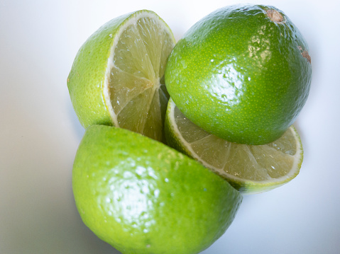 Ripe lime fruits with slices and lime leaves on a gray stone table. Nice fruit citrus background for your projects.