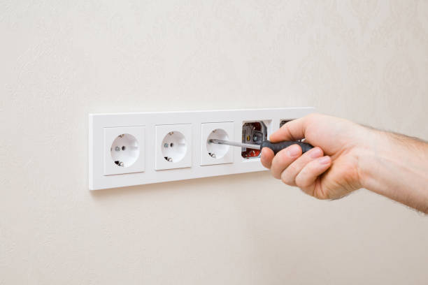 istock Young adult man hands holding screwdriver, screwing and installing new wall socket in white plastic frame. Closeup. Renovation process. Repair work of home. 1362771094