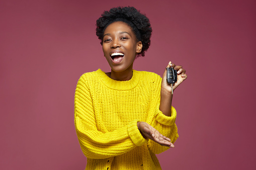 New Car. Excited happy young african american woman holding car keys, celebrating buying auto or win of own automobile. High quality photo