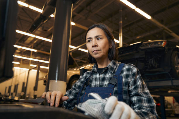 istock Serious brunette woman in mechanic uniform looking puzzled at workplace 1362772404