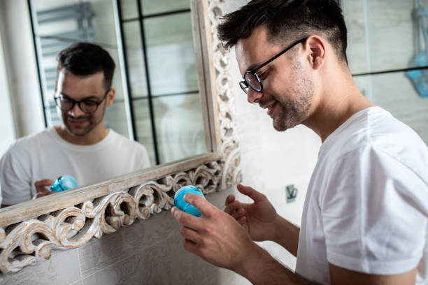 istock Young man going through morning routine in the bathroom applying face cream. 1362786277