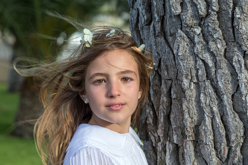 Madrid Spain. April 26, 2014. Headshot of young blonde girl looking at camera next to tree trunk
